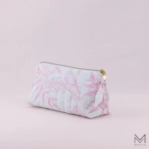 quilted cosmetic bag with zipper and custom zipper pull on a light pink background