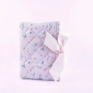 A soft, quilted lilac Bible sleeve with a delicate floral pattern featuring small flowers and leaves, tied with an elegant pink cotton bow. Designed to protect and carry your Bible, this charming sleeve adds a touch of sophistication and care to your spiritual essentials. Perfect for personal use or as a thoughtful gift.